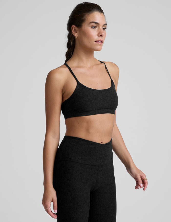 Woman wearing a black sports bra and leggings on a light gray background.