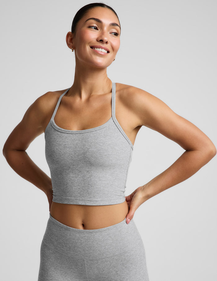 A woman modeling a light gray heather cropped tank top and matching high-waisted leggings against a solid light gray background.