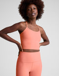 Woman wearing a peach-colored cropped tank and leggings on a plain background.