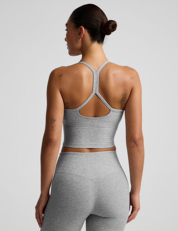 A woman modeling a light gray heather cropped tank top and matching high-waisted leggings against a solid light gray background.