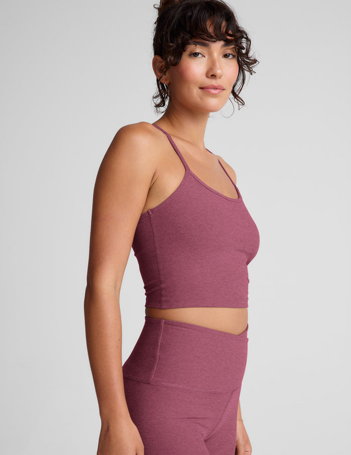 Woman wearing a purple racerback cropped tank and leggings against a plain background.