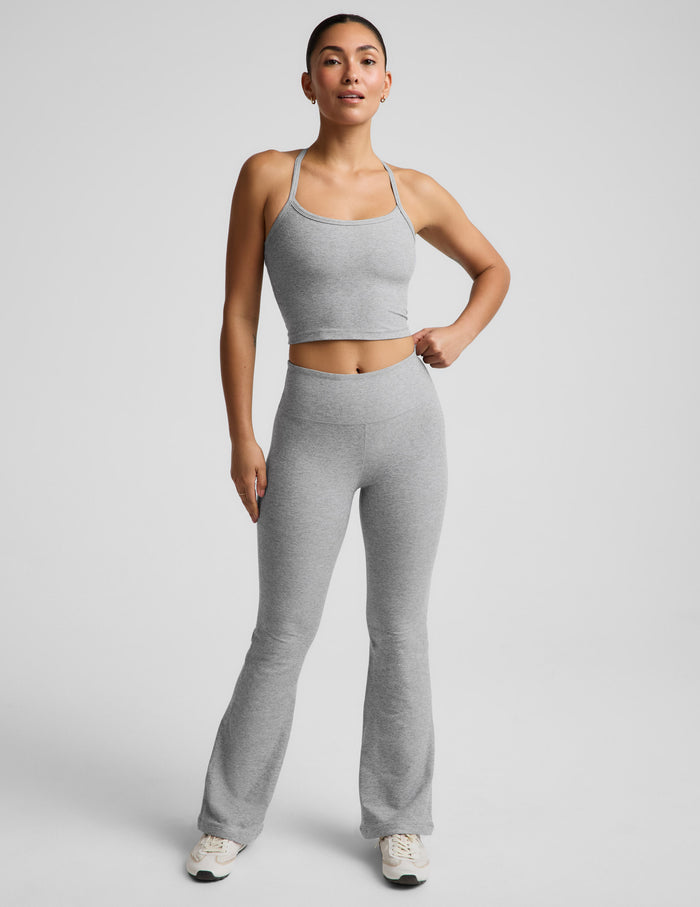 A woman modeling a light gray heather cropped tank top and matching high-waisted leggings against a solid light gray background.