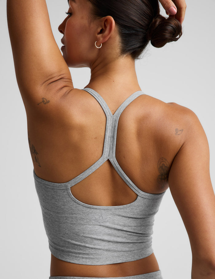A woman modeling a light gray heather cropped tank top and matching high-waisted leggings against a solid light gray background.