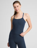 A woman modeling a dark heathered blue athletic tank top and matching leggings against a light gray studio background.