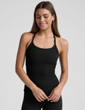 woman wearing a full length racerback tank top and leggings against a plain background.