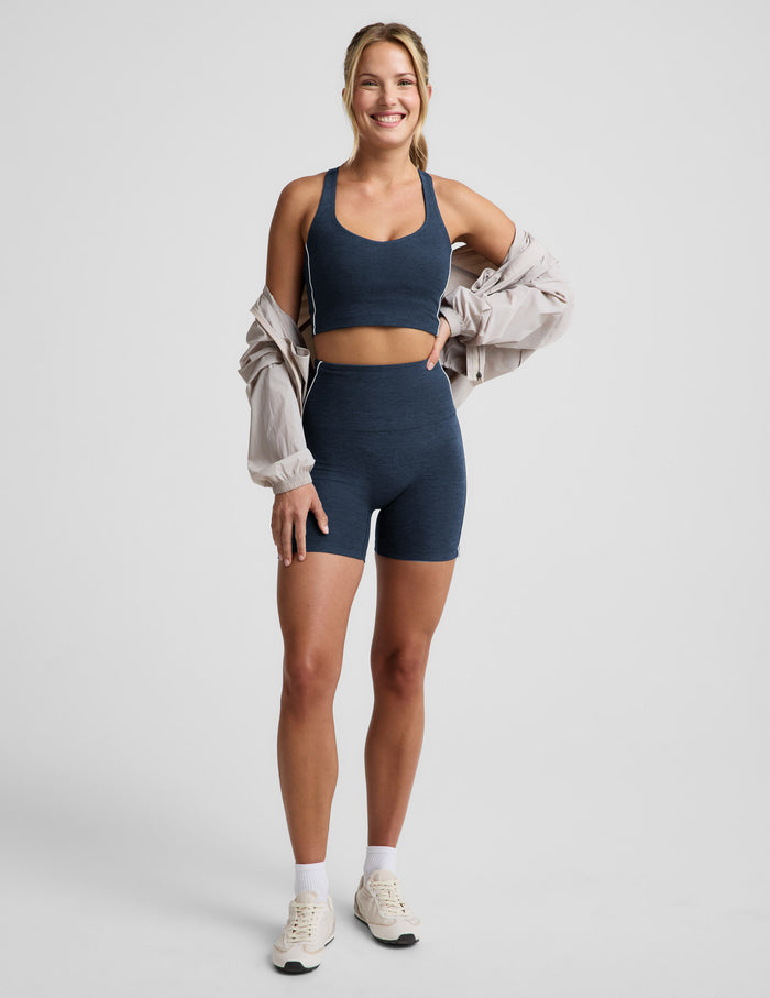 Woman wearing a navy blue cropped tank and biker shorts against a plain background.