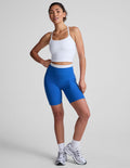 Blue Spacedye Trophy 5" Short with white contrast waistband and piping, shown on a model with a white tank and sneakers.