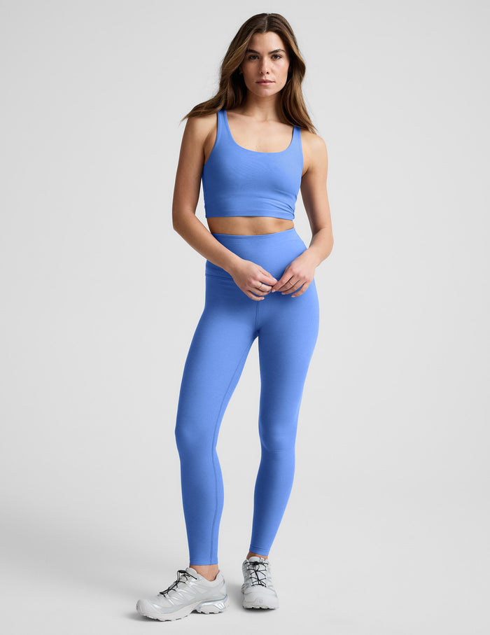 Woman wearing a blue athletic outfit on a light gray background.