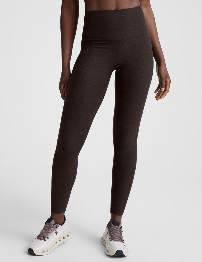 woman wearing a brown sports bra and long leggings set on a white background.
