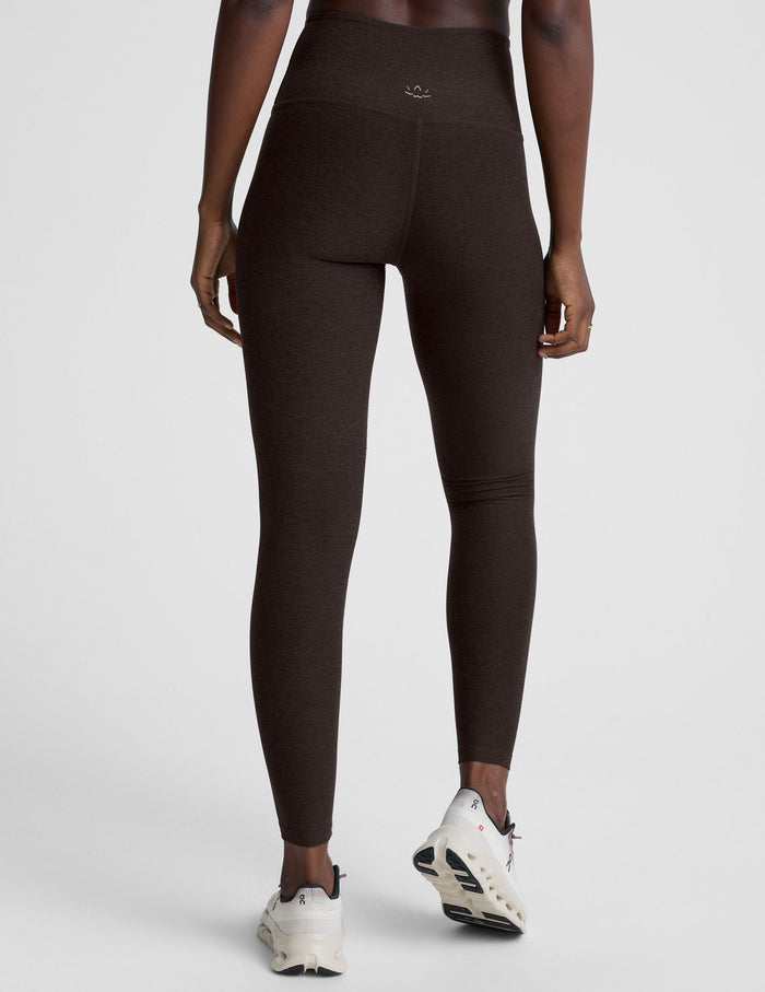 woman wearing a brown sports bra and long leggings set on a white background.