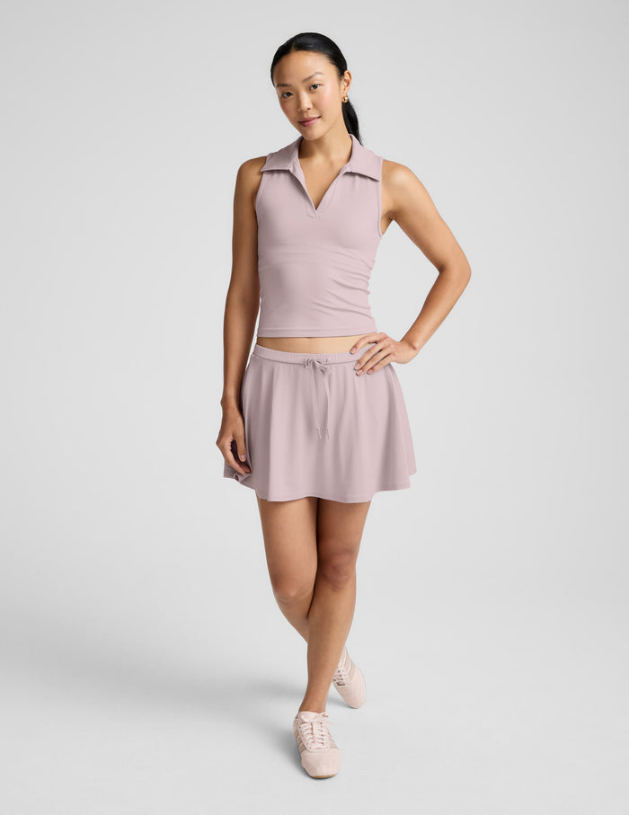 A model wearing the pink Sport Active Drawcord Mini Skirt with an A-line fit, drawstring waist, and matching polo top.