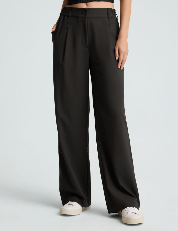 Black Status Wide Leg Trouser featuring a relaxed, flowy fit, mid-rise elastic waist with belt loops, and button fly.