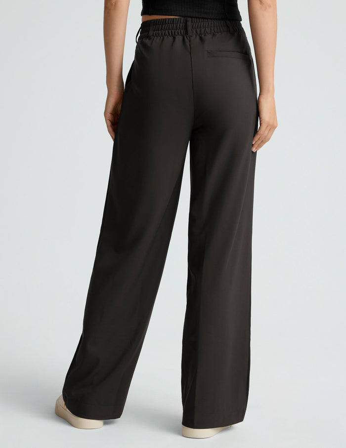 Rear view of black Status Wide Leg Trouser featuring an elastic waistband, belt loops, welt pocket, and loose straight leg.