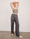 Model in charcoal Status Wide Leg Trouser with front pleats and a flowy fit. Mid-rise waist with belt loops and button fly.