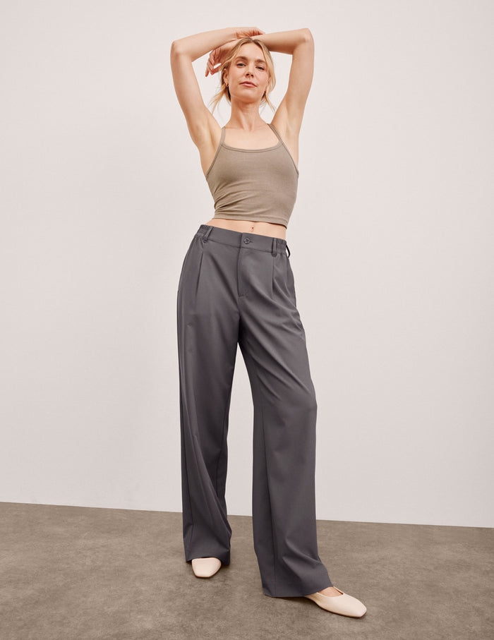 Model in charcoal Status Wide Leg Trouser with front pleats and a flowy fit. Mid-rise waist with belt loops and button fly.