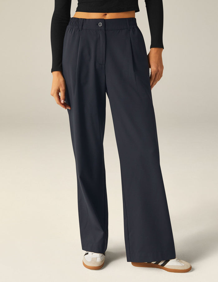 Woman wearing Black Status Wide Leg Trousers™ paired with a black long-sleeve top and white sneakers.