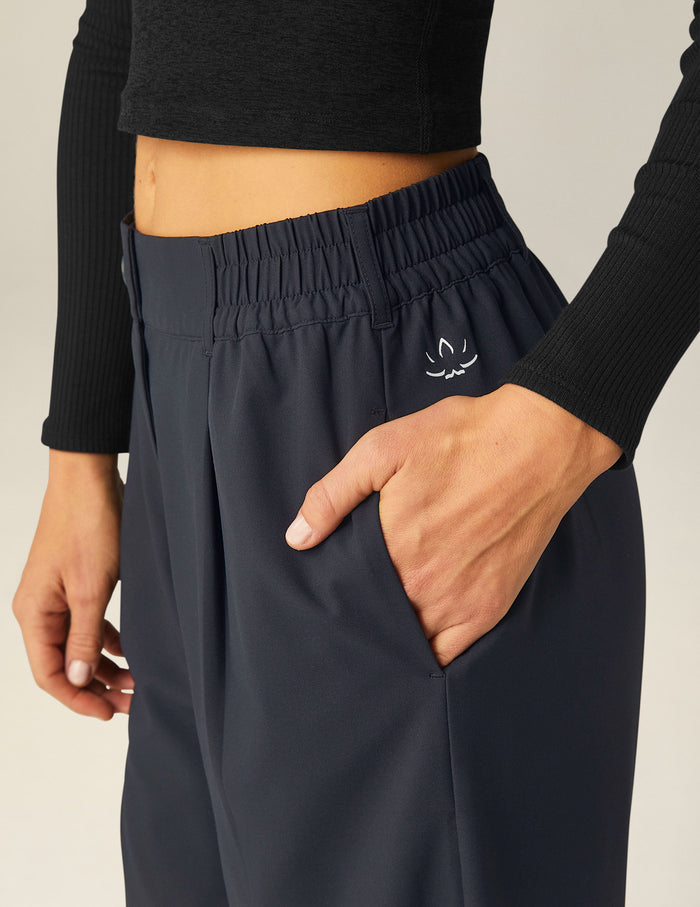 Close-up of woman wearing Black Status Wide Leg Trousers™ with hand in pocket, paired with a black long-sleeve crop top.