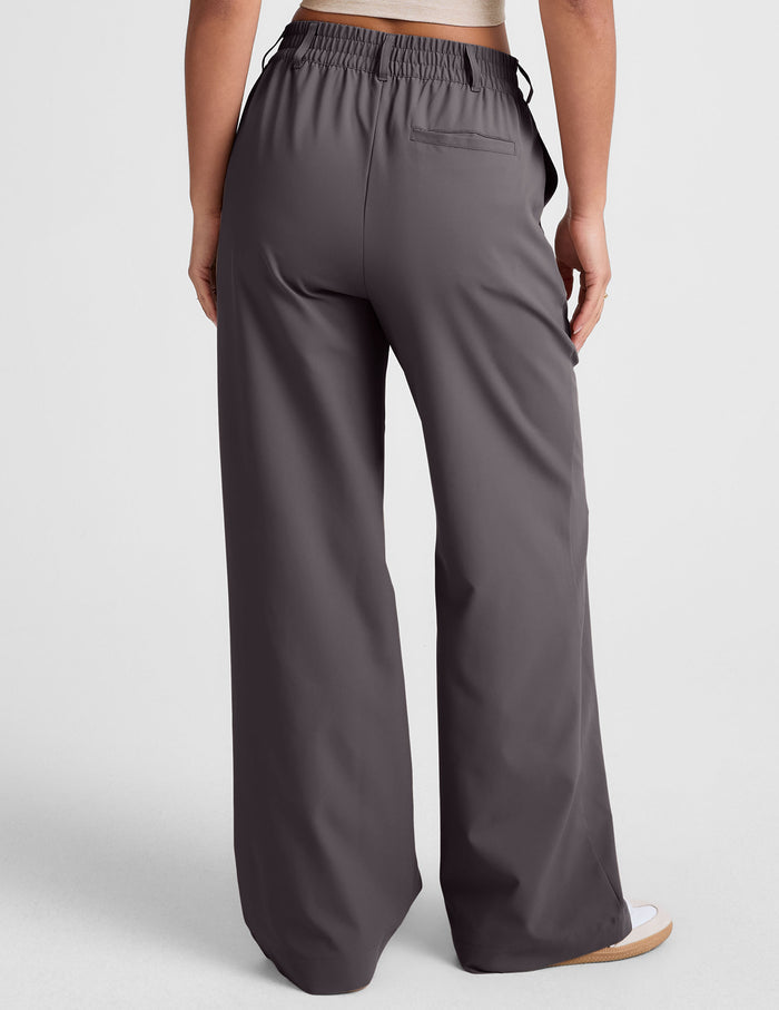 Back view of a person wearing dark grey Status Wide Leg Trousers with an elastic waistband, belt loops, and a back welt pocket.