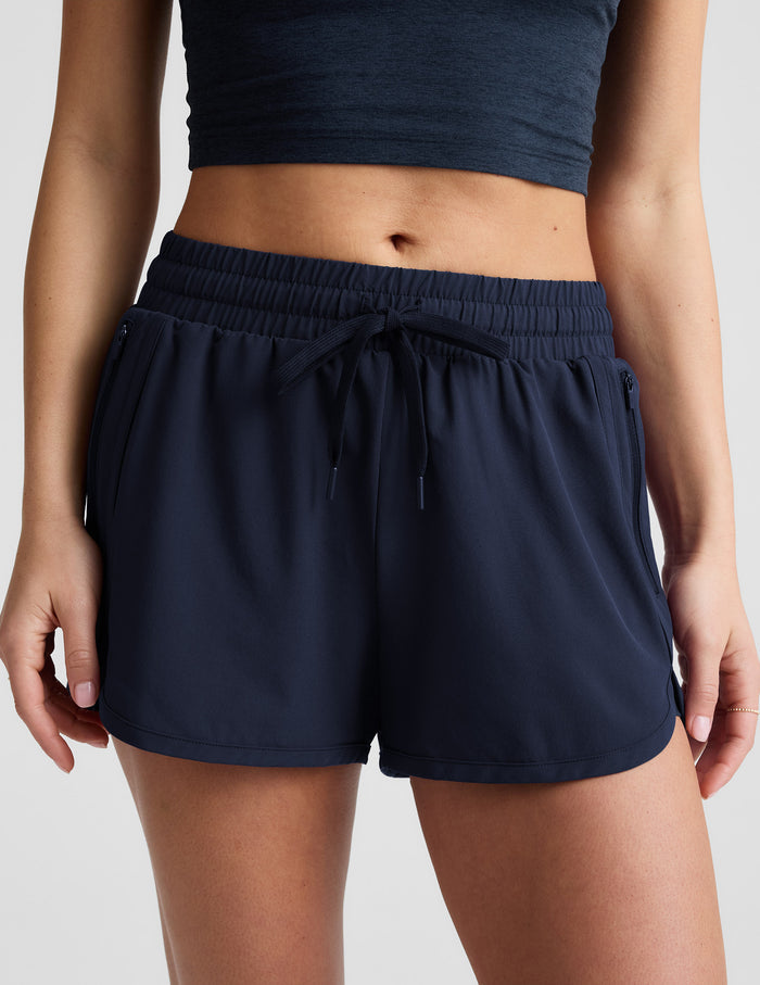 Woman wearing a blue cropped tank top and blue shorts against a plain background.