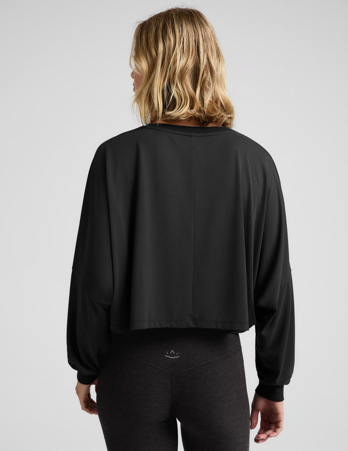 Woman wearing a black long sleeve top and leggings against a plain studio background.