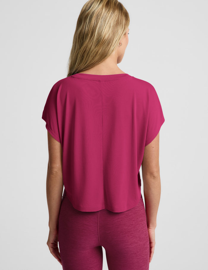 Woman wearing a magenta cropped short sleeve and magenta pintuck capri pants against a plain background.