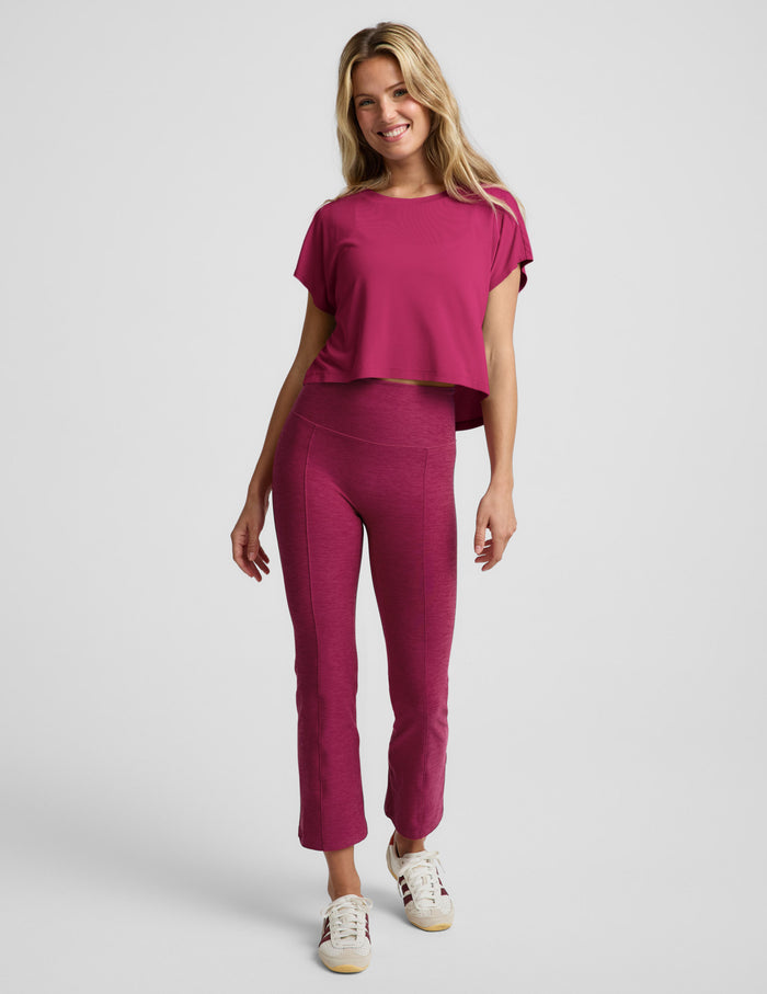 Woman wearing a magenta cropped short sleeve and magenta pintuck capri pants against a plain background.
