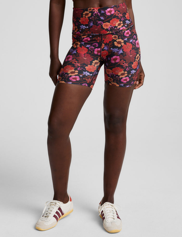 Summer Bouquet SoftMark Keep Pace Biker Short in a dark floral print with a high-waisted, snug fit on a model.