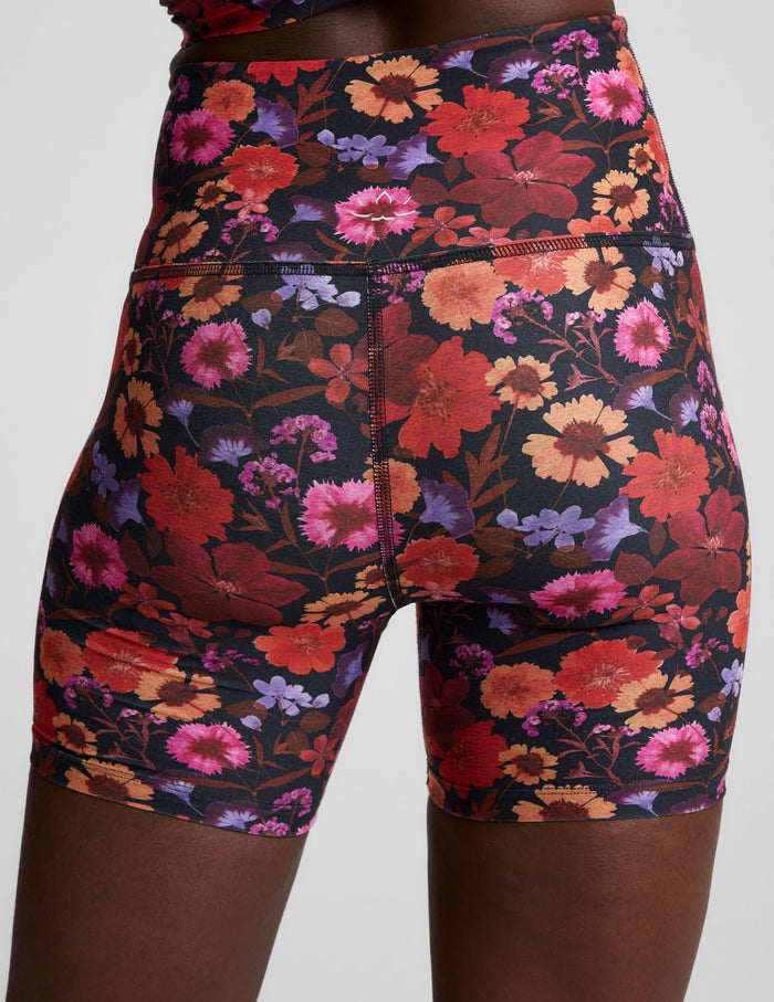 Rear view of Summer Bouquet SoftMark Keep Pace Biker Short in a vibrant red and orange floral print on black fabric.