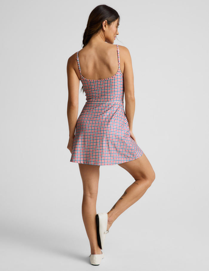 Woman wearing a gingham dress against a light gray background.