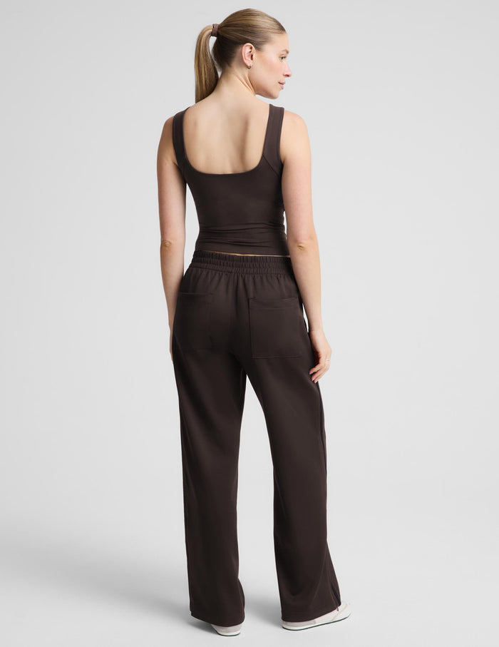 A woman modeling a dark brown sleeveless tank top and matching wide-leg pants against a light gray studio background.
