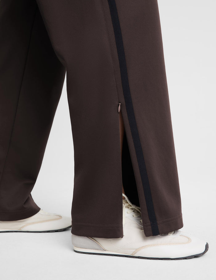A woman modeling a dark brown sleeveless tank top and matching wide-leg pants against a light gray studio background.