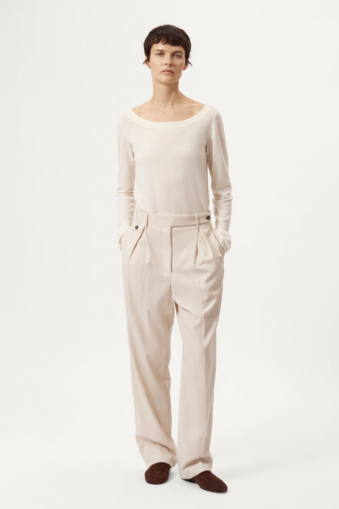 Person wearing a white sweater and black pants on a white background