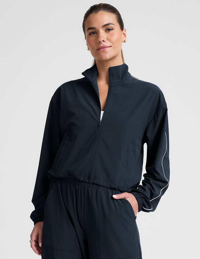 model wearing a blue track jacket with white piping detail on a light gray background.