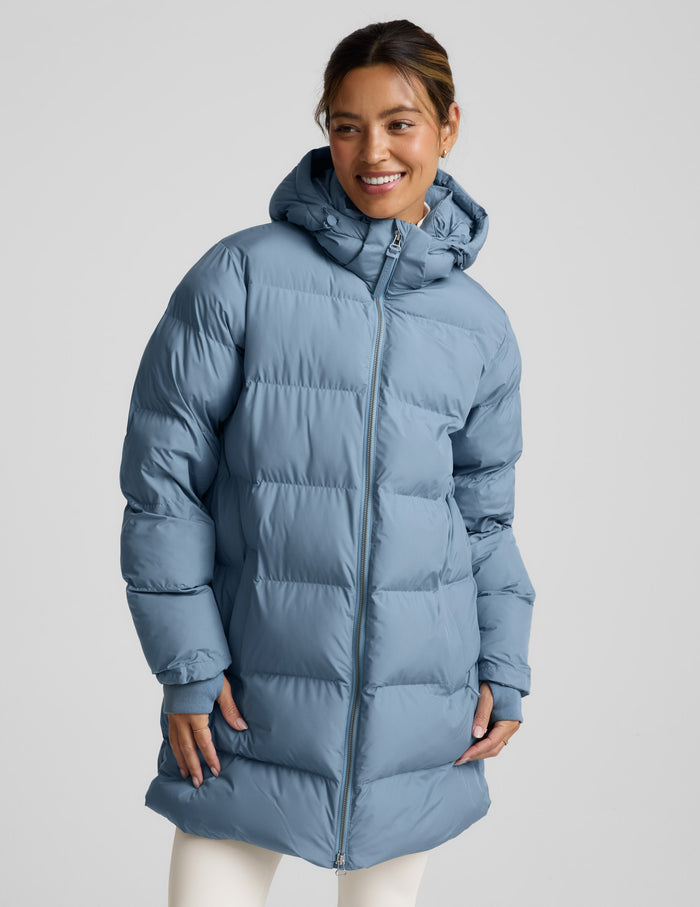 Woman wearing a blue puffer coat on a light gray background