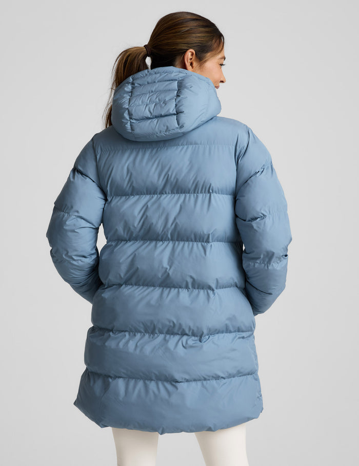 Woman wearing a blue puffer coat on a light gray background