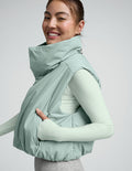 Woman wearing a light blue cropped puffer vest on a plain background.