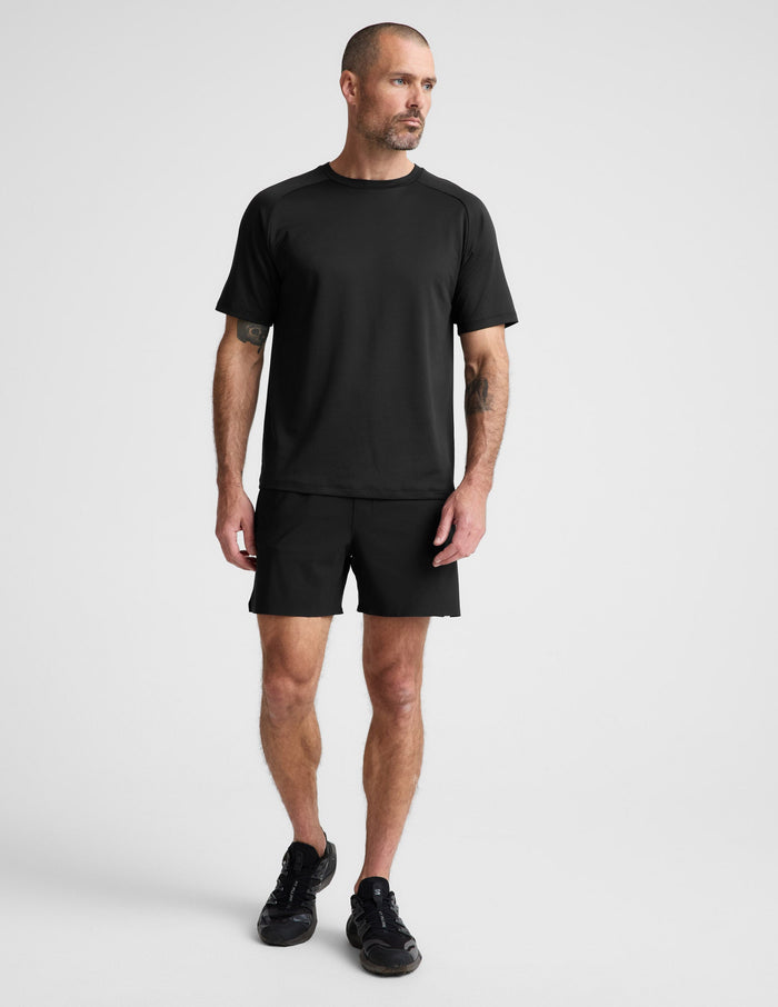 Man wearing Black WarpLite Range Lined Short™ with an elastic waistband, paired with a black t-shirt and sneakers.