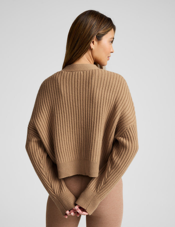 woman wearing a brown button up ribbed cardigan against a plain background.