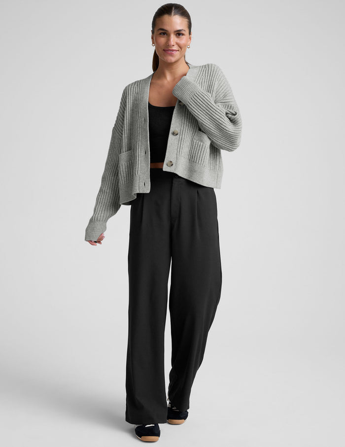woman wearing a gray ribbed cardigan on a plain background.